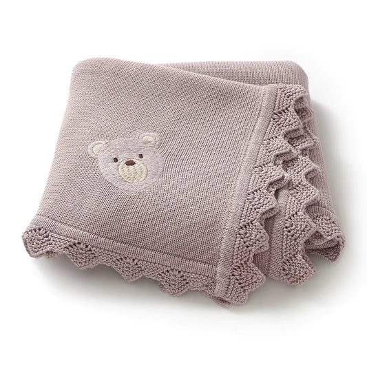 Purple knitted blanket with a teddy bear design on a white background