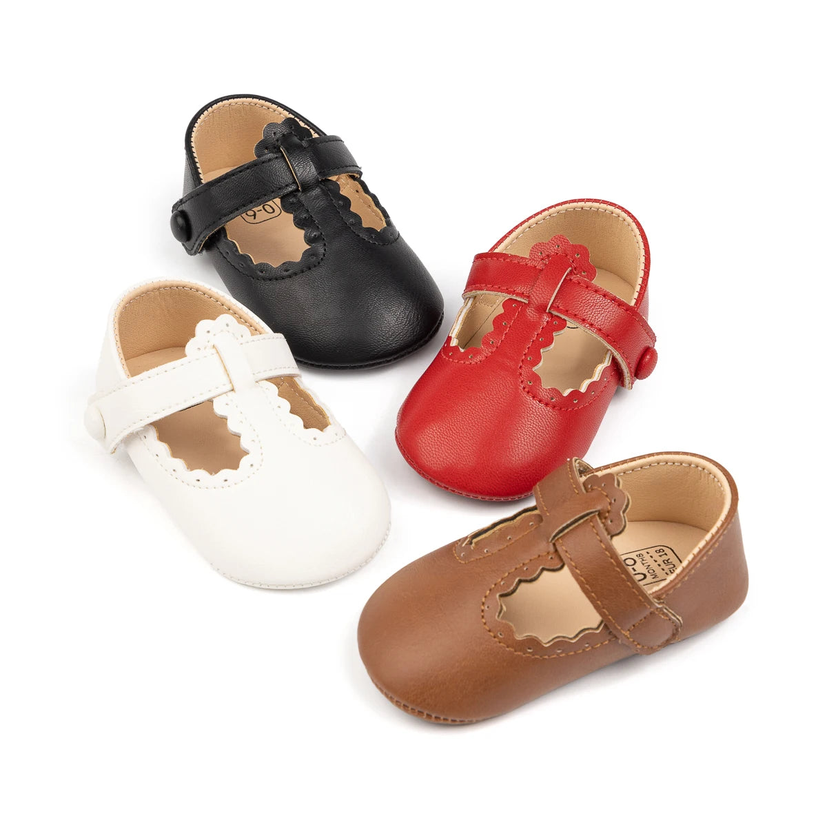 Four pairs of baby girl T-strap Mary Jane crib shoes arranged together in black, white, red, and brown.