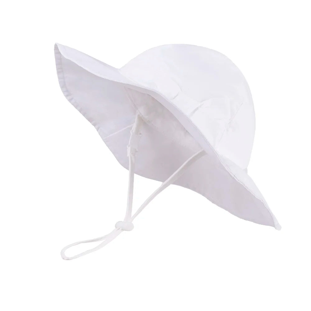 Crisp white 100% cotton wide brim summer sun hat for baby girls featuring a matching decorative side bow and white adjustable safety strap.