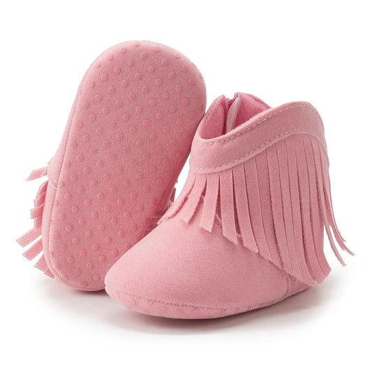 Pink infant fringe suede moccasin booties showing the soft, textured anti-slip dotted sole on a white background.