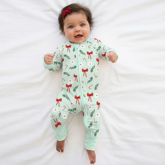 Baby girl model wearing red bow headband and Kidsely mint Christmas candy cane and red bows print bamboo viscose zipper romper sleeper