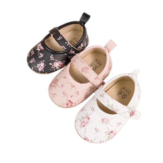 Three pairs of cottagecore baby girl floral Mary Jane shoes in black, pink, and white.