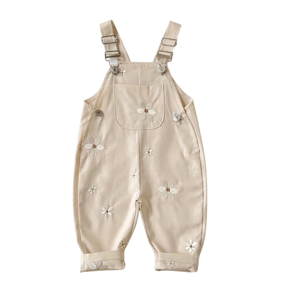 Cream beige Kidsely toddler overalls featuring embroidered white daisies and a front chest pocket, displayed flat against a white background.