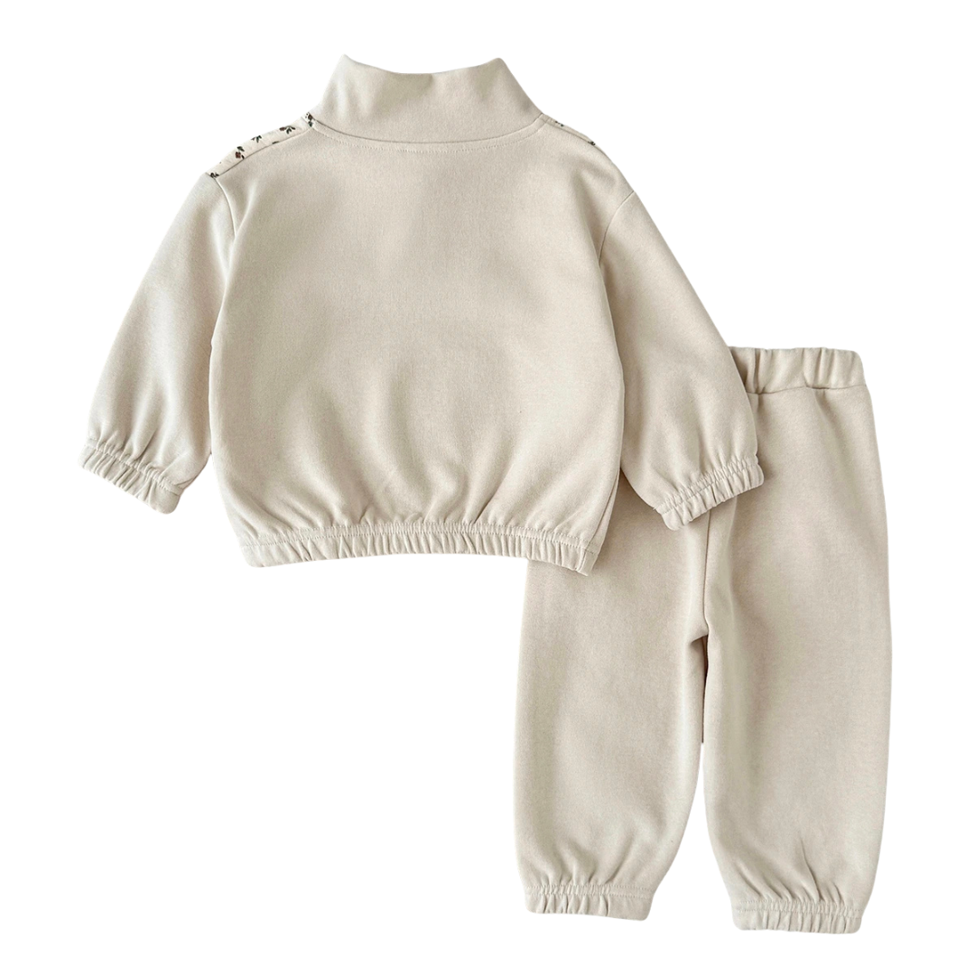 Back view of the baby and toddler girls cream sweatshirt and jogger set laid flat on a white background, showing the solid cream back.