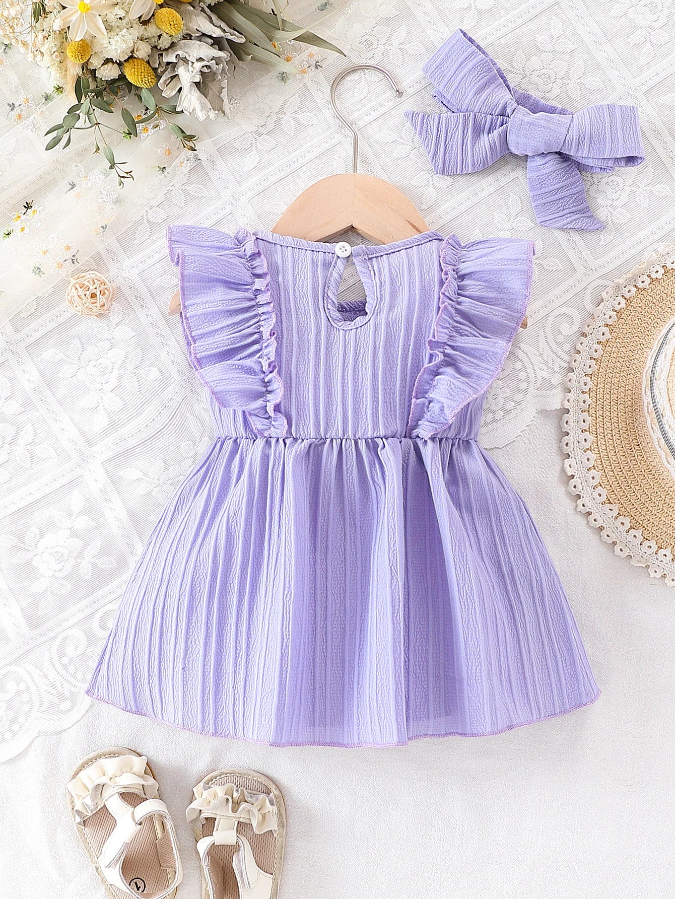 Back view of the light purple baby dress on a hanger, demonstrating the convenient back-button closure for easy dressing.