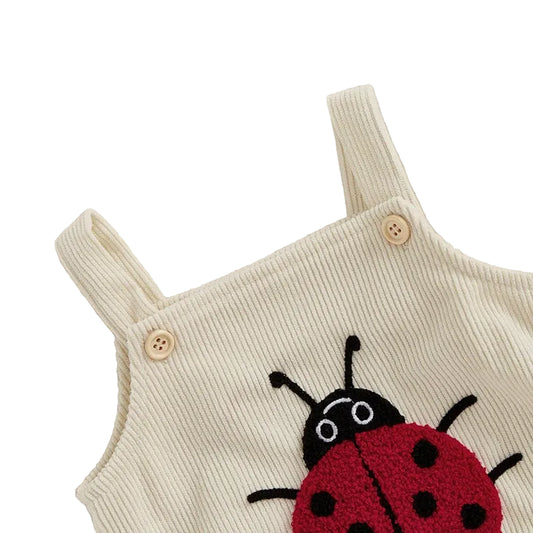 Close-up of the adjustable wooden-style shoulder buttons on the Little Lady ladybug romper.