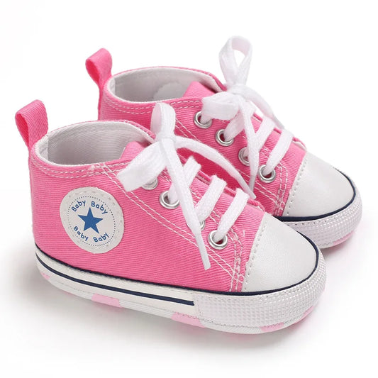 Light pink canvas baby sneakers with soft soles for infant girls' first steps.