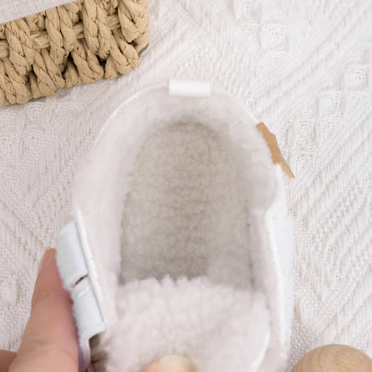 Close-up inside view of white baby sneakers highlighting the thick, cozy faux-fleece lining.
