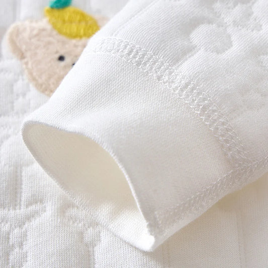 Close up detail of soft ribbed sleeve cuff and textured fabric on cotton baby romper.