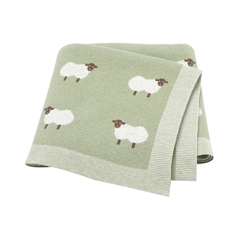 Close-up of a Sage Green knitted cotton baby blanket featuring a reversible white lamb design and premium ribbed edging.