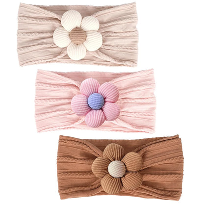 three-pack of baby nylon headbands featuring oat, caramel, and petal pink with a lavender flower center