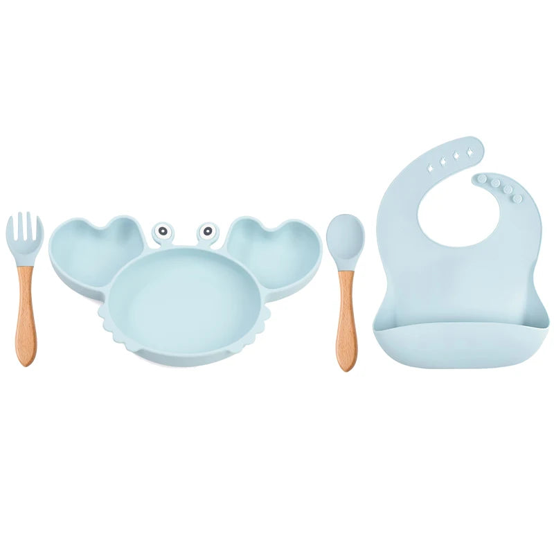 Children's dining set with blue plate, bowl, fork, spoon, and bib on a white background