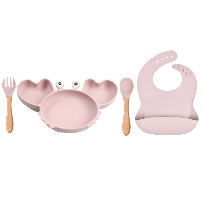 Pink baby feeding set with plate, bowl, spoon, and bib on a white background