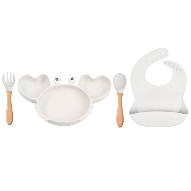 Set of children's tableware including a plate, fork, spoon, and bib on a white background