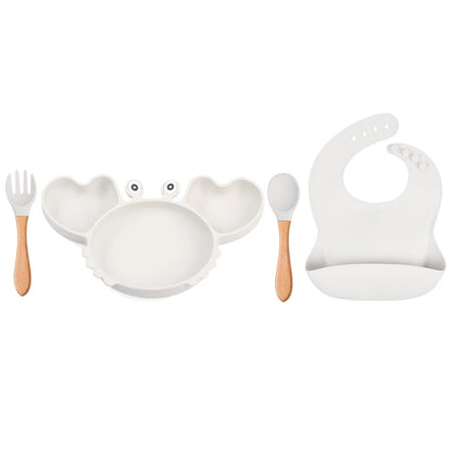 Set of children's tableware including a plate, fork, spoon, and bib on a white background