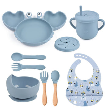 Complete 9-piece baby feeding set laid out flat, featuring a crab plate, bowl, bib, sippy cup with straw, snack lid, and four utensils.
