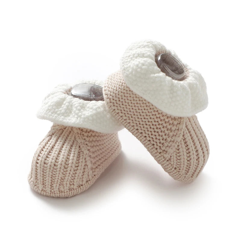 Pair of knitted baby booties with white tops and beige bodies on a white background