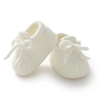 Pair of white knitted baby shoes on a white background