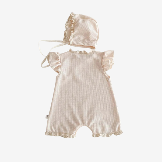 Baby romper with matching bonnet on a white background