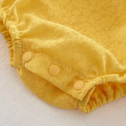 Close-up of a yellow baby romper with buttons on a white background