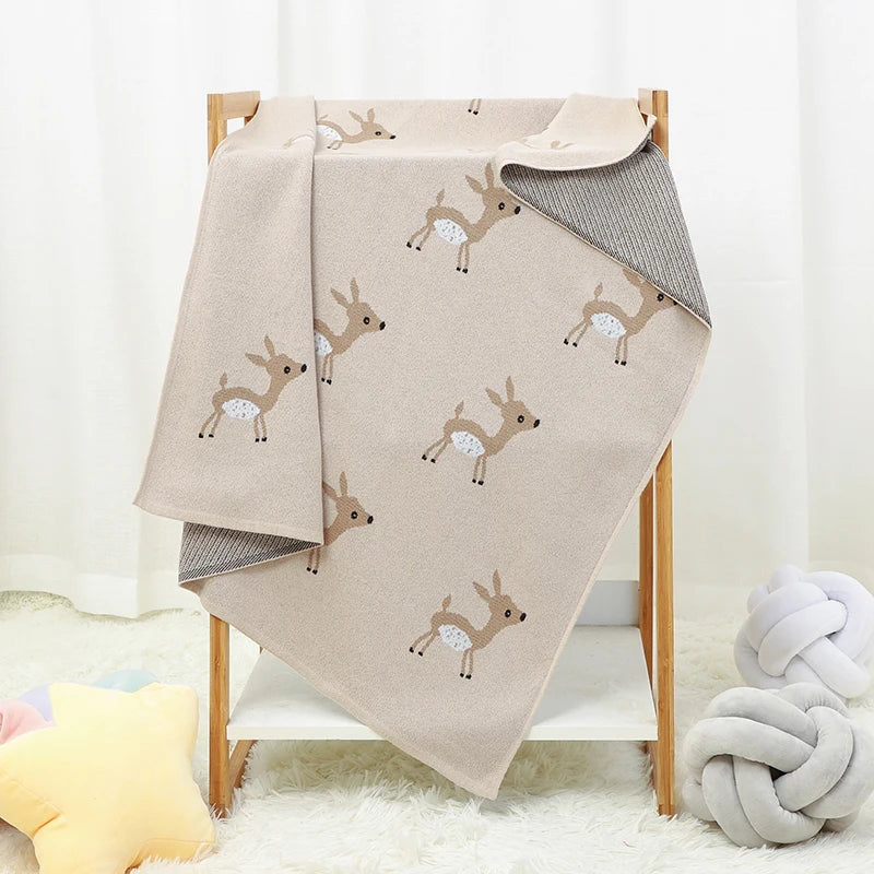 A beige cotton knit blanket draped over a blanket rack.