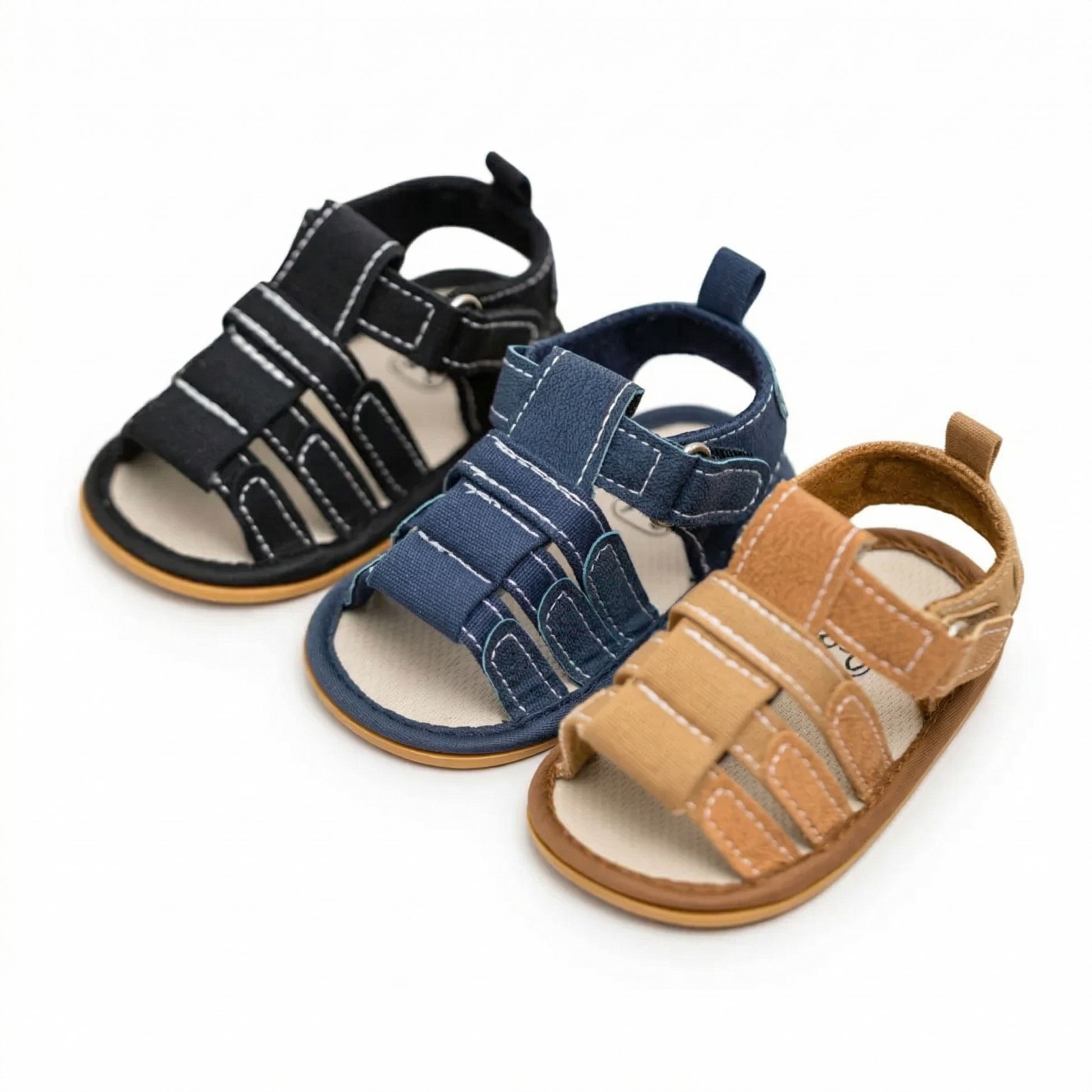 Three pairs of baby boy first walker sandals in tan, navy blue, and black displayed together, featuring non-slip rubber soles and adjustable velcro straps for infants 0-18M.