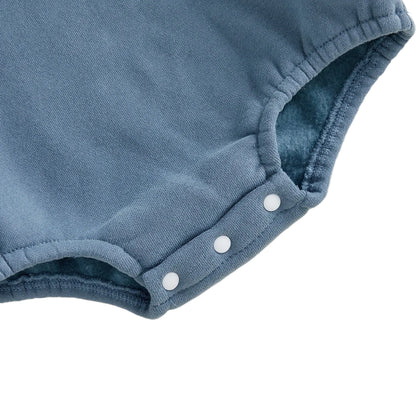 Close-up view of the three white bottom snap button closures for easy diaper changes on the blue fleece romper.