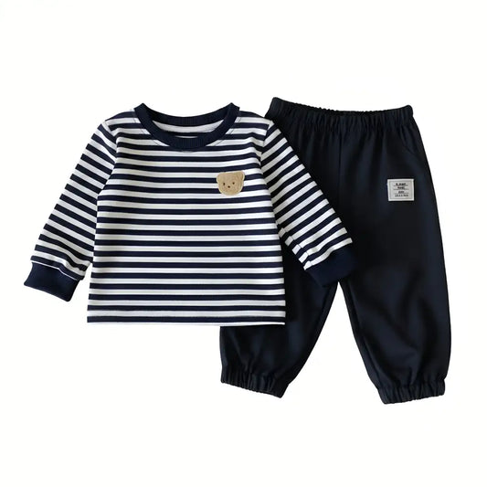 Flat lay of baby boy and toddler 2-piece outfit featuring a navy and white striped long sleeve top with a fleece bear patch and matching navy jogger pants.