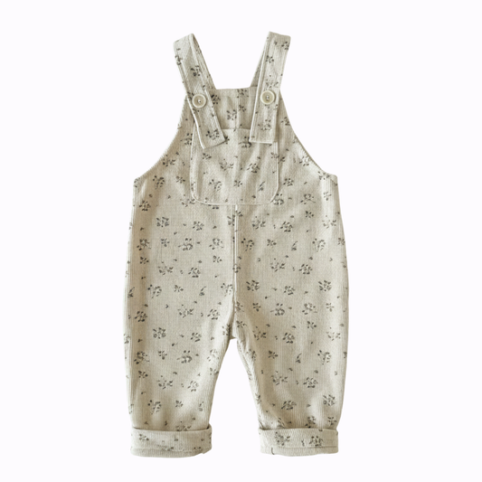 Front view of baby girl cream-colored corduroy overalls with a vintage floral print and wood-style buttons.