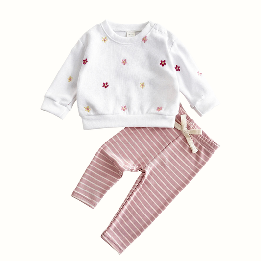 Front view of toddler girl floral sweatshirt and striped pants set hanging on a wooden hanger.