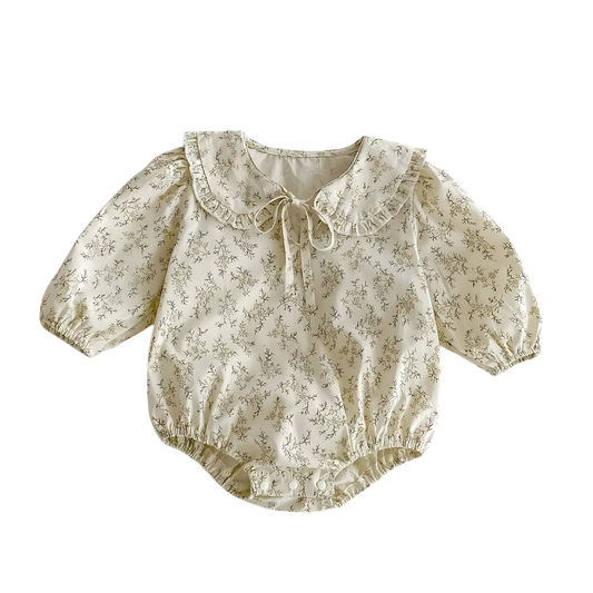 Flat lay view of a cream long-sleeved baby girl bodysuit featuring a sage green wildflower print, ruffled Peter Pan collar with a front tie, and snap button closure.