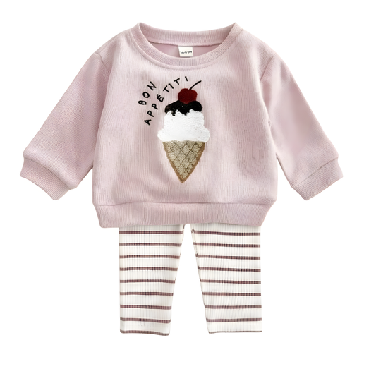 Flat lay view of baby girl two-piece outfit set including a pink long-sleeve pullover with textured ice cream cone design and "Bon Appétit" text, paired with coordinated striped ribbed leggings.