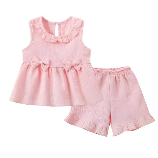 2-piece baby girl sleeveless top and shorts set in soft rose pink muslin cotton with ruffle collar and bow accents.