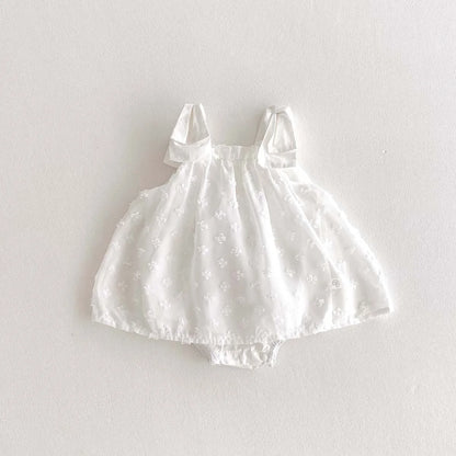 White baby dress with bow straps on a light gray background