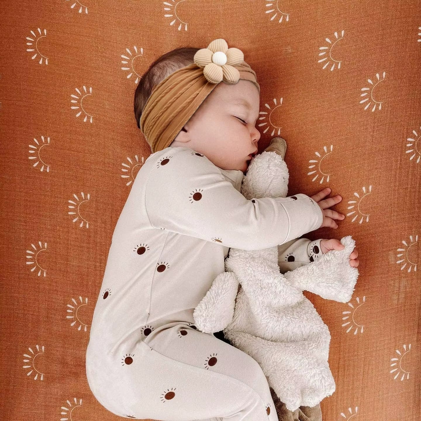 baby wearing a caramel colored floral headband while sleeping
