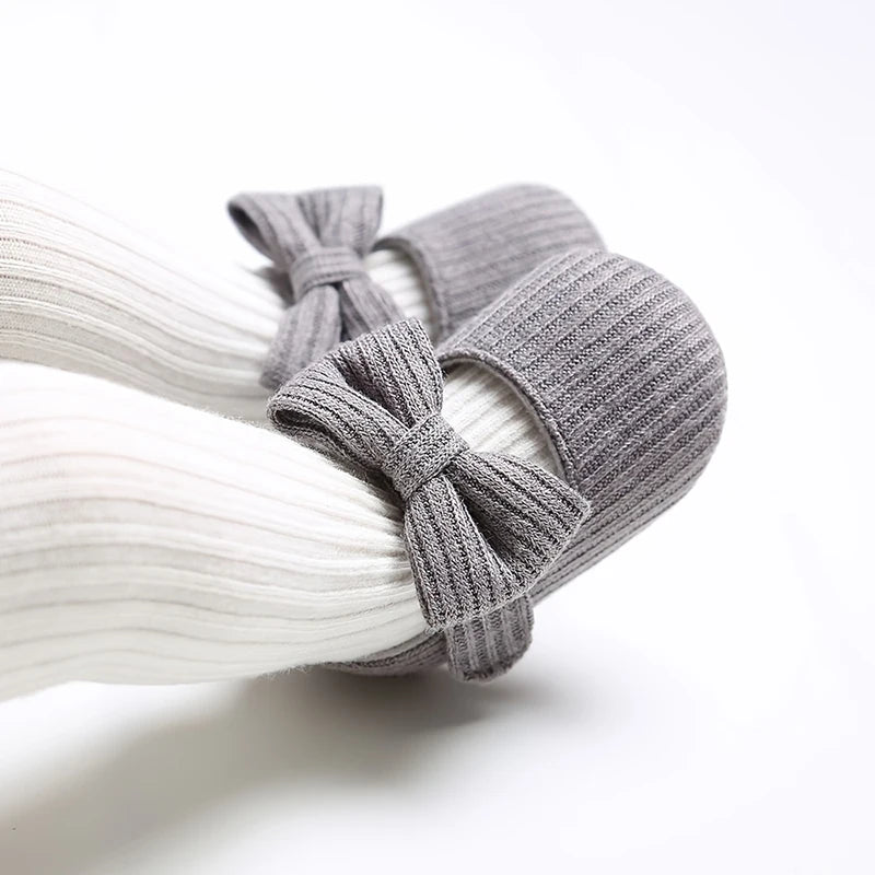 Baby wearing grey ribbed knit soft sole Mary Jane crib shoes with white ribbed tights.