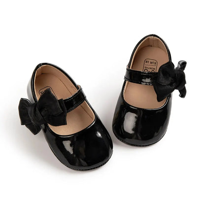 Black glossy patent PU leather baby girl dress shoes with bowknot detail and secure hook and loop strap.