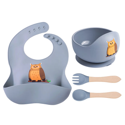 Children's dining set with bib, bowl, fork, and spoon featuring owl designs on a white background.