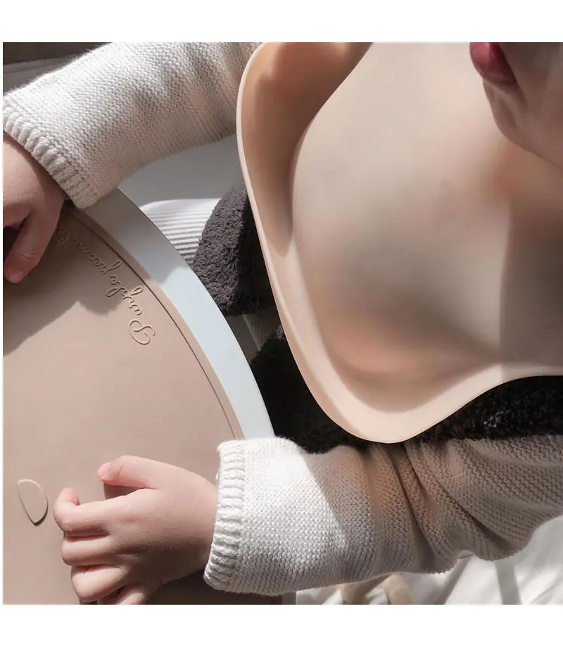 Person wearing a beige bra with a child's hand on the strap