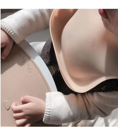 Person wearing a beige bra with a child's hand on the strap