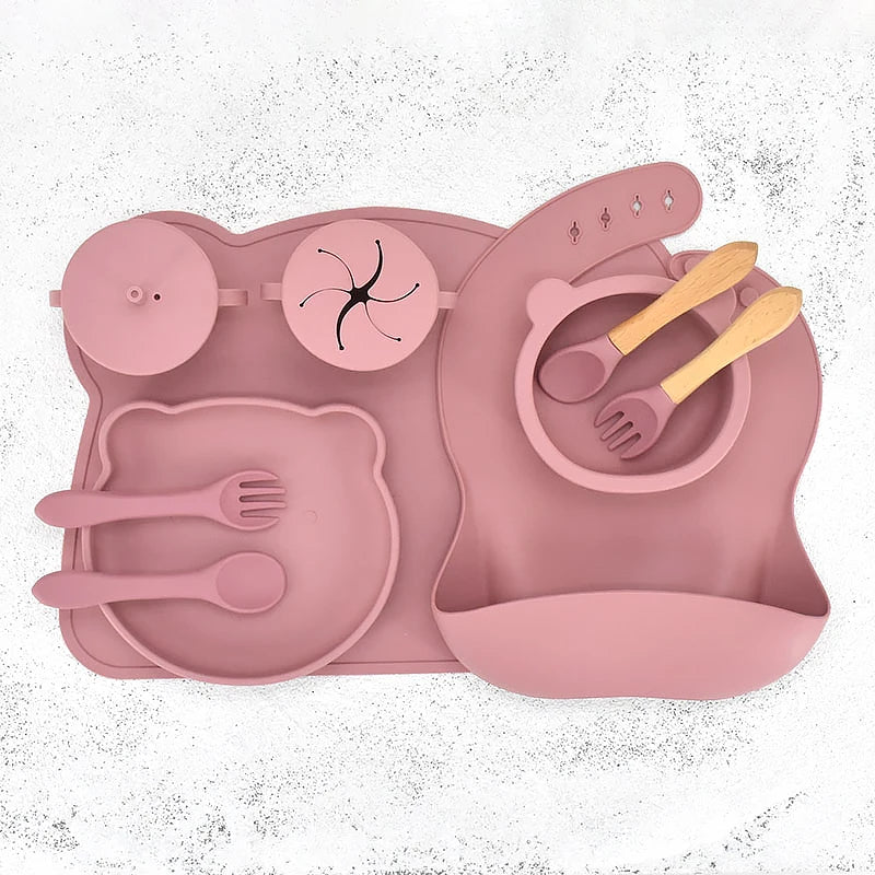 Pink silicone placemat with cutlery and bowl on a white background