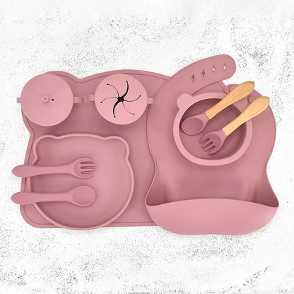 Pink silicone placemat with cutlery and bowl on a white background