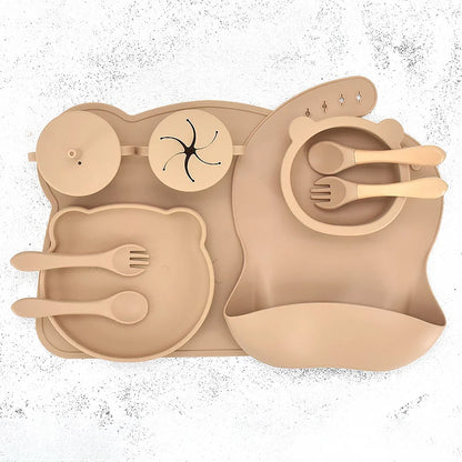 Khaki silicone placemat with cutlery and bib on a white background
