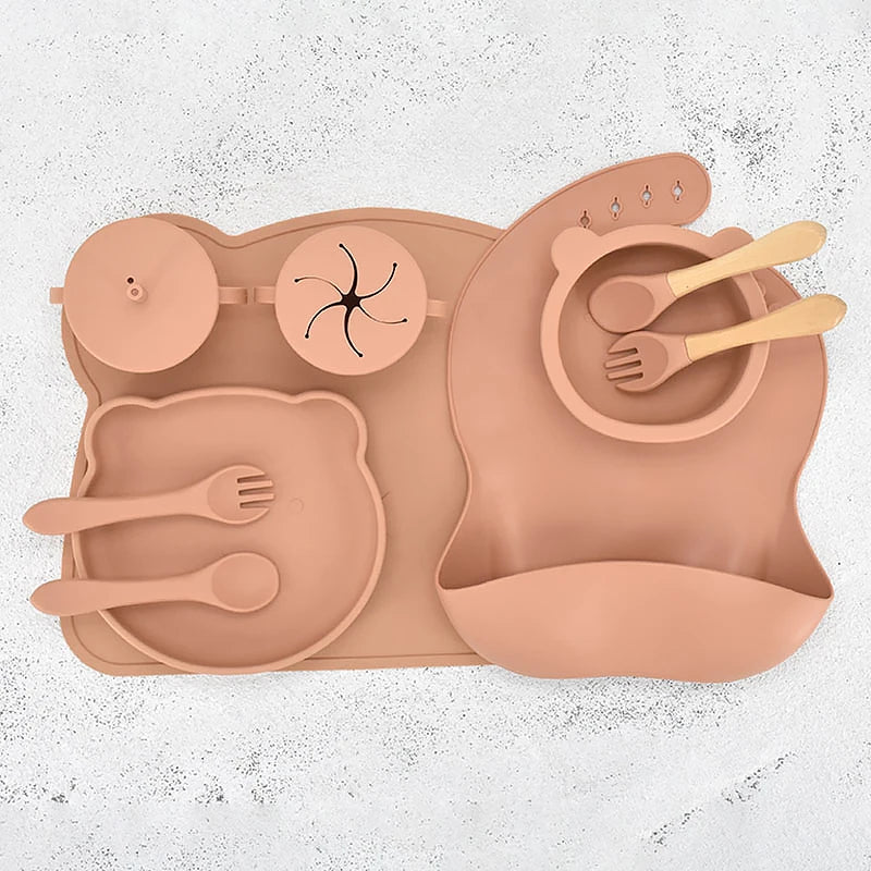 Orange children's silicone placemat with cutlery on a textured white background