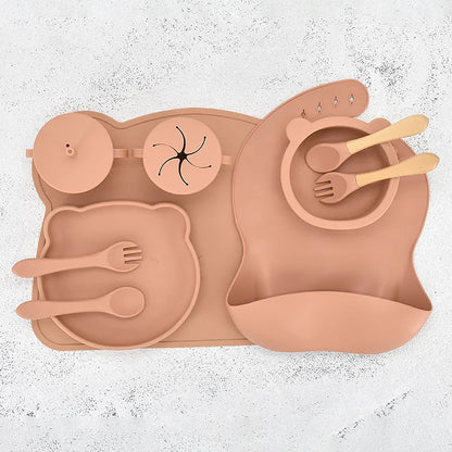 Orange children's silicone placemat with cutlery on a textured white background