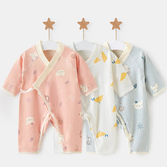 Three 100% cotton newborn kimono rompers hanging on wooden star hangers. The set shows the pink woodland, sunny whales, and blue woodland animal prints, highlighting the side-tie wrap design perfect for coming home outfits.