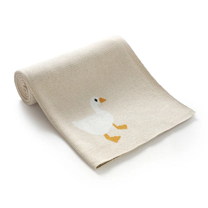 Folded beige blanket with a goose illustration on a white background