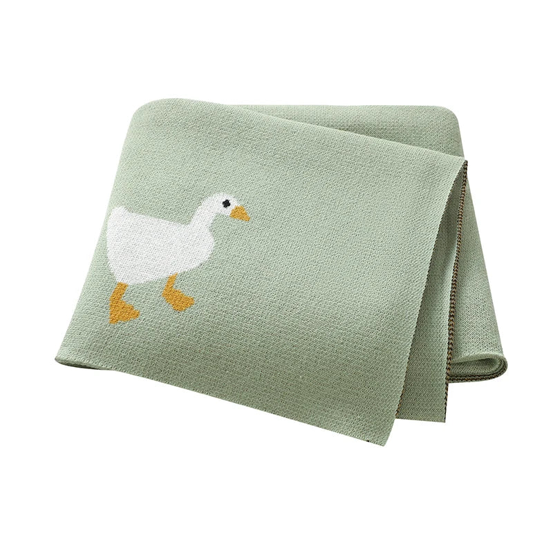 Folded green blanket with a goose design on a white background