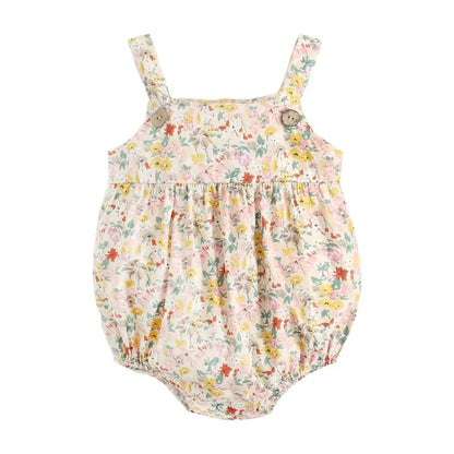 Flat lay view of a cream and yellow floral print cotton baby sunsuit with a bubble silhouette and decorative wood buttons.