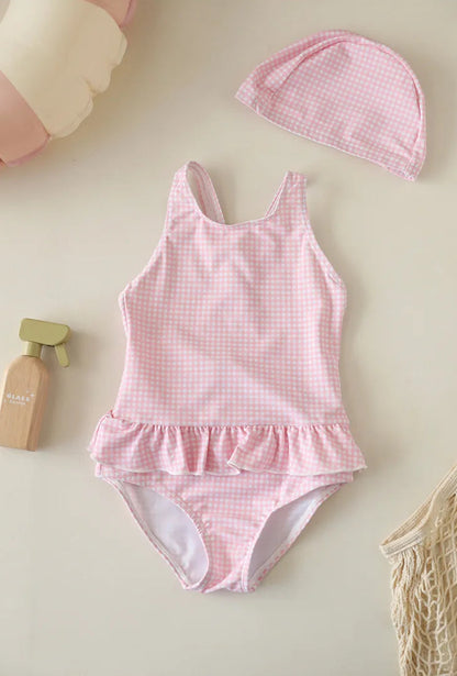 Soft Blush Pink gingham one-piece bathing suit for infant and toddler girls, featuring a ruffled waist and a matching pink checkered sun bonnet.